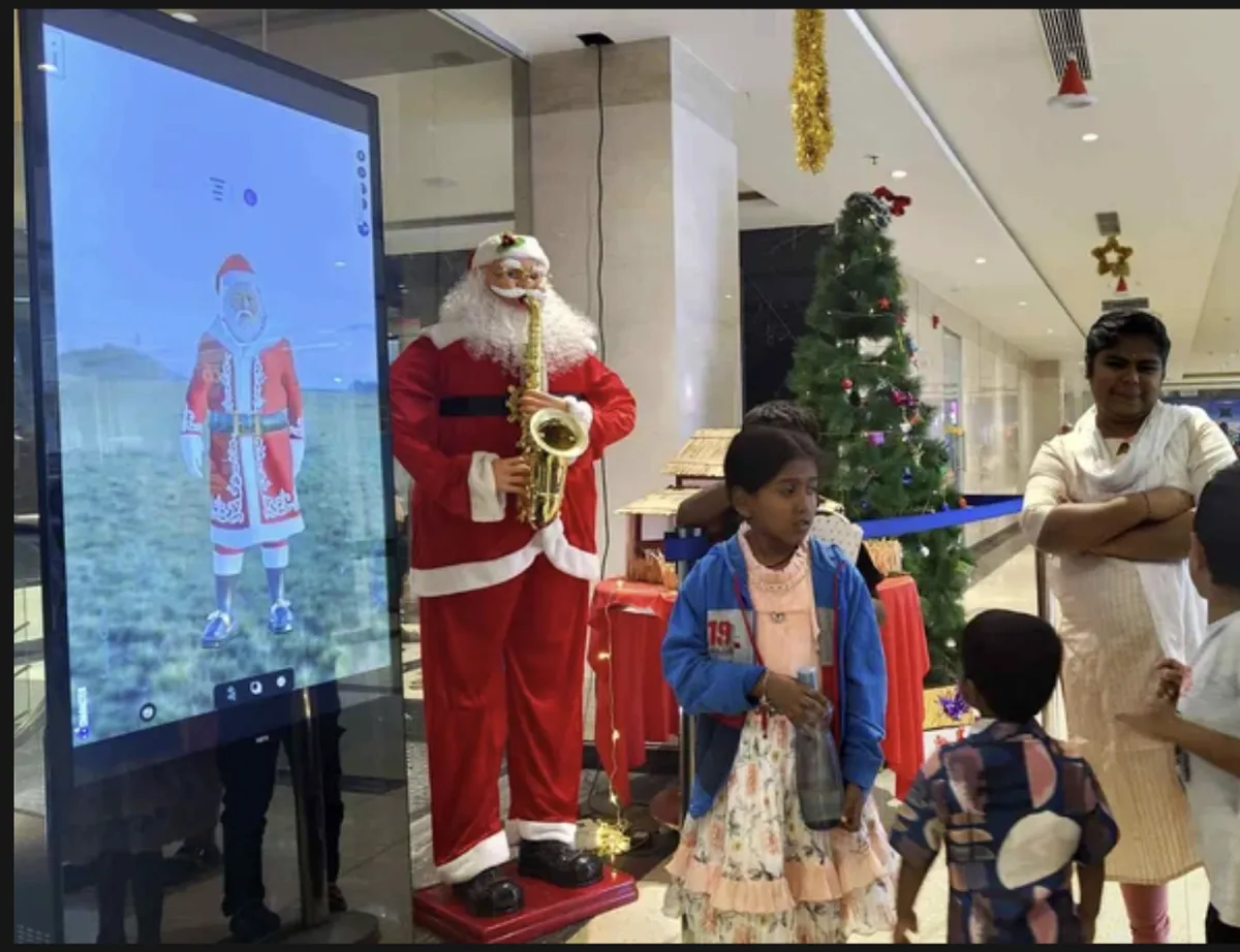 Children gathered around a large screen showing a virtual character at a mall in Coimbatore
