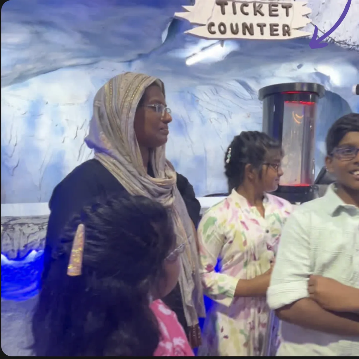 Guests talking to a hologram unit at the ticket counter of an indoor snow attraction